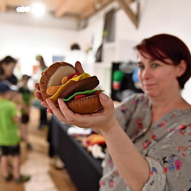 Hier sieht man mich wie ich einen realistisch aussehenden Hamburger in der Hand vorzeige.